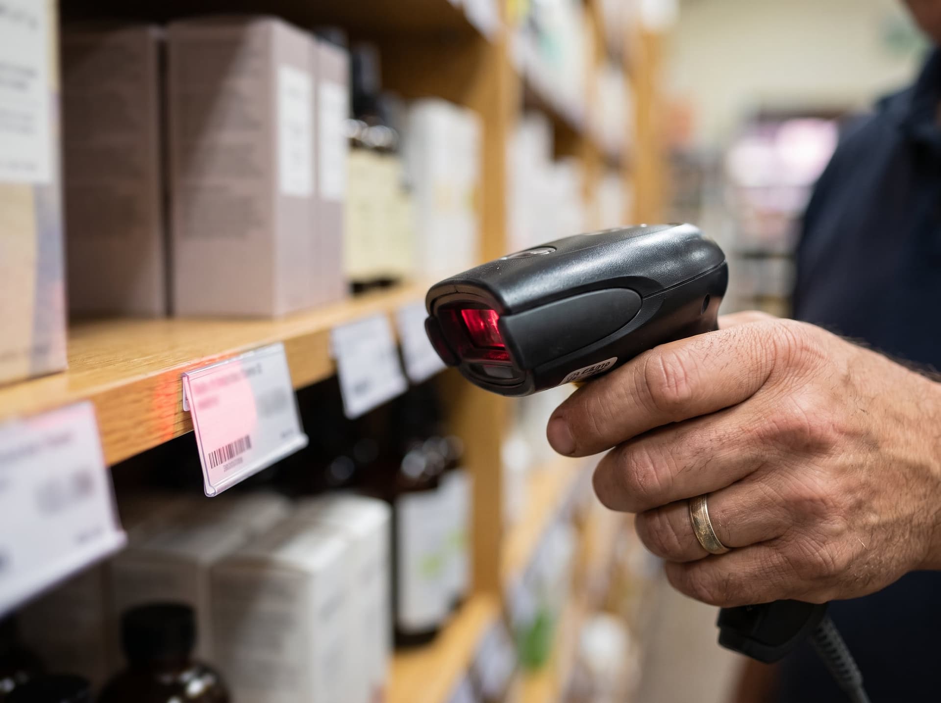 A handheld barcode scanner reading a shelf price tag